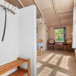Raum mit Holzdecke, Tisch, Stühle und Fenster. Ankleidebereich mit Bänke und Haken.