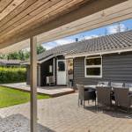 Terrasse mit Tisch und Stühlen vor einem Haus mit Holzveranda und Garten.