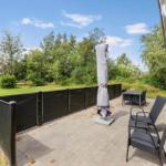 Terrasse mit Garten, Tisch, Stühlen und geschlossenem Sonnenschirm.