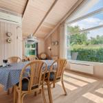 Esszimmer mit Holzwand, Tisch mit Tischdecke und Stühlen, großes Fenster mit Blick auf Grün.