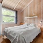 Schlafzimmer mit Bett, Schrank und Stuhl. Holzwände und Fenster mit Blick auf Grün.