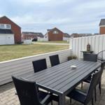Terrasse mit Tisch und Stühlen, Blick auf Grünfläche und Häuser.