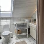 Badezimmer mit Toilette, Waschbecken und Wickeltisch unter Dachschrägen.
