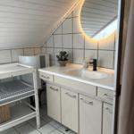 Badezimmer mit Waschbecken, Spiegel und Babywanne unter Dachschräge.