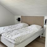 Schlafzimmer mit Doppelbett, Holzpaneelen und schrägem Dach