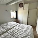 Schlafzimmer mit Doppelbett, Fenster, Stuhl und Kleiderschrank.