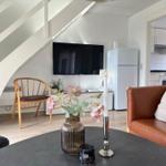 Wohnzimmer mit Sofa, Fernseher und Küchenbereich im Hintergrund.