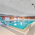 Indirekter Pool mit Rutsche und Metallstufen in einem Innenbereich mit Ziegelwand.