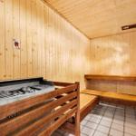 Sauna mit Holzwand und Bänken, Grill mit Kohle und Bodenfliesen.