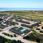 Aerial view of vacation homes near water with pool and green fields.
