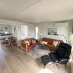 Wohn- und Essbereich mit braunen Sofas, schwarzer Ledersessel und Holzboden.