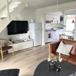 Wohnzimmer mit braunem Sofa, Fernseher und Küchenbereich im Hintergrund.