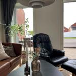 Ein Wohnzimmer mit braunem Sofa, schwarzer Ledersessel und Tisch mit Vasen.