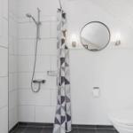 Badezimmer mit Dusche, Toilette und runden Spiegeln an der Wand.