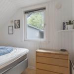 Schlafzimmer mit Bett, Schrank und Fenster. Wandgestaltung mit Bildern und Pflanze.