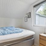 Schlafzimmer mit Bett, Fenster und Kleiderschrank. Weiße Wände und Holzdetails.