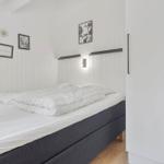 Schlafzimmer mit Bett, Wandbildern und Kleiderschrank.