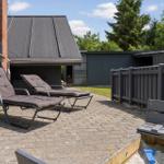 Terrasse mit zwei Liegestühlen, Holzbank und Sandkasten. Hinterhof mit Zaun und Grünfläche.
