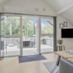 Wohnraum mit Glasfront zum Balkon, TV und Esstisch.