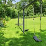 Schaukelanlage im Garten mit Grasfläche und Blumenbeete
