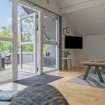 Wohnbereich mit Holzboden, TV und Blick auf Balkon mit Grill.