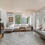Wohnzimmer mit Holzdecke, Kamin und großen Fenstern. Sofa, Couch und Tisch.
