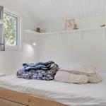 Schlafzimmer mit Bett, Fenster und Regal an der Wand.