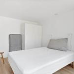 Schlafzimmer mit Bett, Kleiderschrank und Holzstuhl.