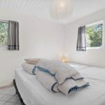 Schlafzimmer mit Bett, zwei Fenstern und einer Deckenleuchte.