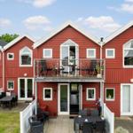 Rotes Haus mit Balkon und Terrasse mit Gartenmöbeln und Pflanzen.