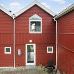 Rotes Holzhaus mit Eingangstür und kleinem Gartenbereich.