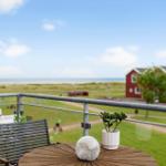 Terrasse mit Tisch und Stuhl, Blick auf Grünfläche und rote Häuser.