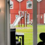 Von der Terrasse aus sieht man einen Spielplatz mit Rutsche vor roten Häusern.