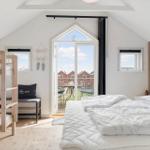 Schlafzimmer mit Doppelbett, Etagenbett und Balkontür. Holzwand und hölzerner Boden.