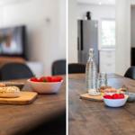 Holztisch mit Donuts und Erdbeeren. Im Hintergrund Kamin und Küchenbereich.