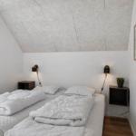 Schlafzimmer mit zwei Betten, weißen Wänden und schrägem Dach