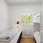 Zimmer mit Einzelbett und Doppelstockbett, Fenster mit Blick auf Grün.