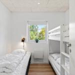 Zimmer mit Etagenbett und Einzelbett, Fenster mit Blick auf Grün.
