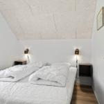 Schlafzimmer mit Doppelbett, zwei Nachttischen und einer schrägen Decke.