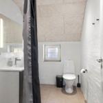 Badezimmer mit Toilette, Waschbecken und Dusche. Fenster mit Glassteinen.