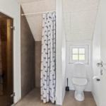 Badezimmer mit Dusche, Toilette und Fenster. Duschvorhang mit Walenmotiv.
