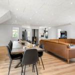 Großes Wohn- und Esszimmer mit braunem Sofa, Esstisch und Kamin.