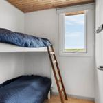 Zimmer mit Doppelstockbett, Holzdecke und Fenster mit Blick auf Grünflächen.