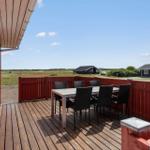 Terrasse mit Tisch und Stühlen, Blick auf Felder und Häuser.