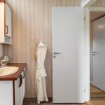 Badezimmer mit Waschbecken, Spiegelschrank und Bademantel an der Wand.