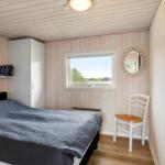 Schlafzimmer mit Bett, Schrank, Stuhl und Fenster.