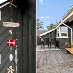 Terrasse mit Holzbank, Tisch und Stühlen. An der Wand hängt ein dekoratives Seil mit dänischer Flagge.