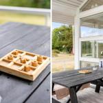 Holzspiel auf dunklem Tisch auf Terrasse mit Blick auf Garten und Haus.