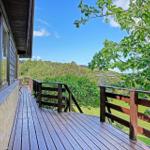 Wooden deck with view of green landscape and blue sky.