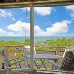 Deck with table and chairs offers ocean view.
